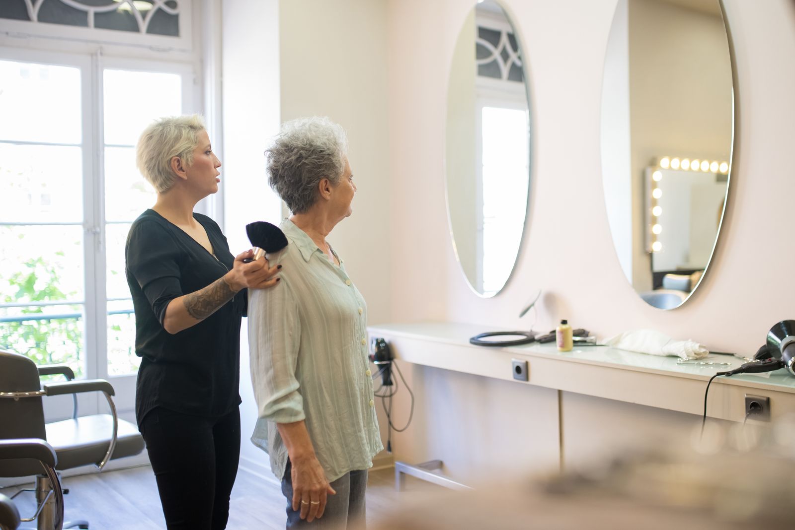 Editorial photograph of a guest and stylist at a salon mirror