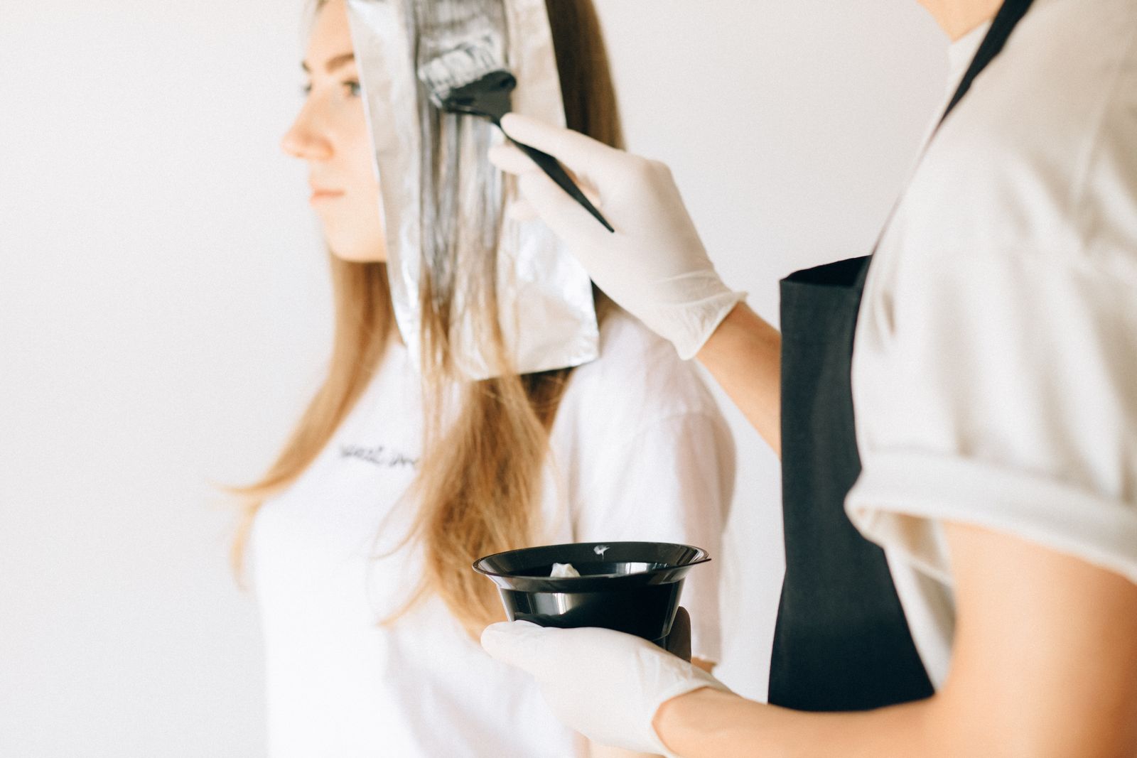Editorial photograph of a stylist applying hair color