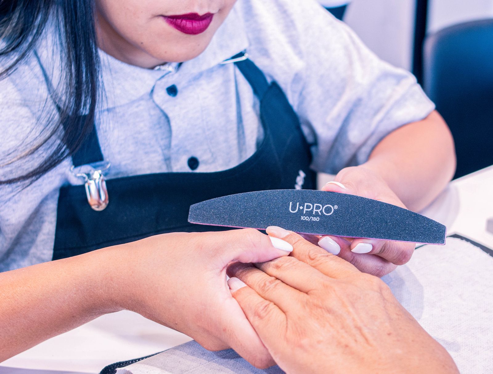 A nail technician filing a client’s nails