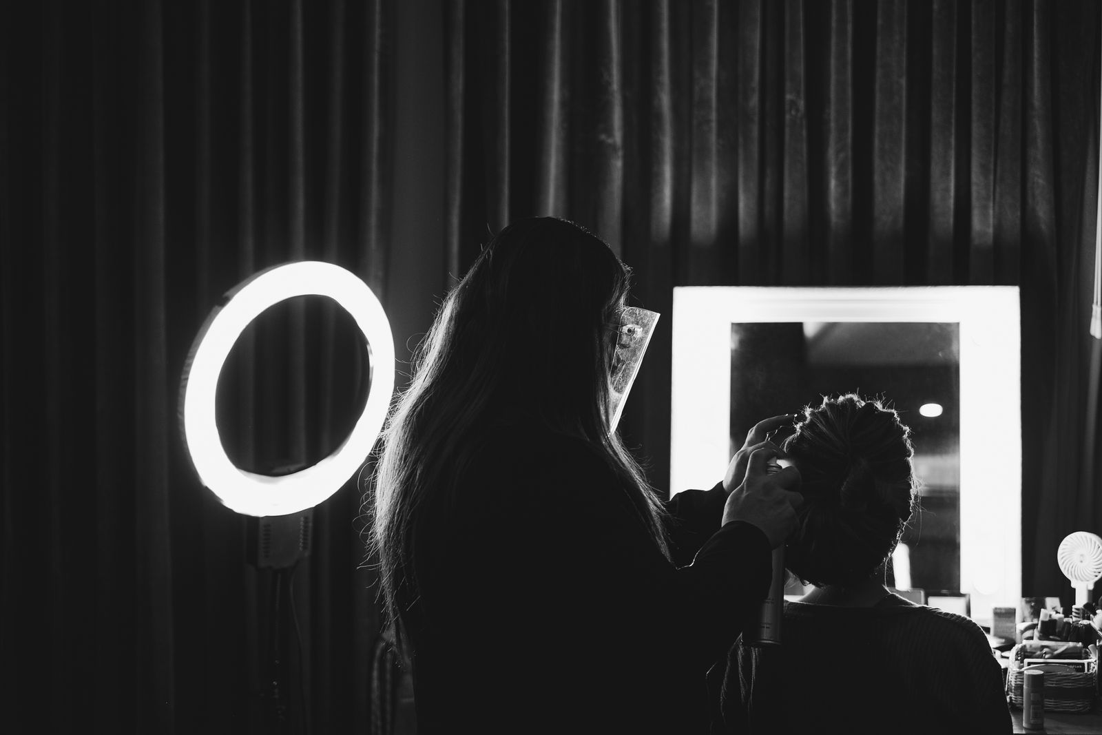 Editorial photograph of a stylist working with a guest at a salon mirror